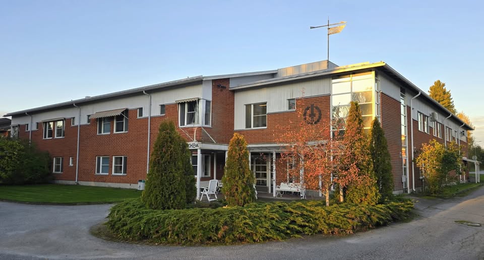 Aurora Cares verksamhetsställe i Nykarleby, en tegelbyggnad med entré och trädgård.